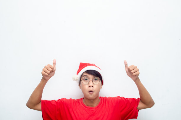 快乐迷人的亚洲男人穿着红色圣诞主题衣服，指着手指，展示一些商品。图片下载