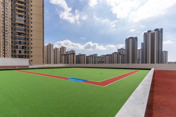 绿色的橡胶操场，旁边是现代化的城市建筑图片下载