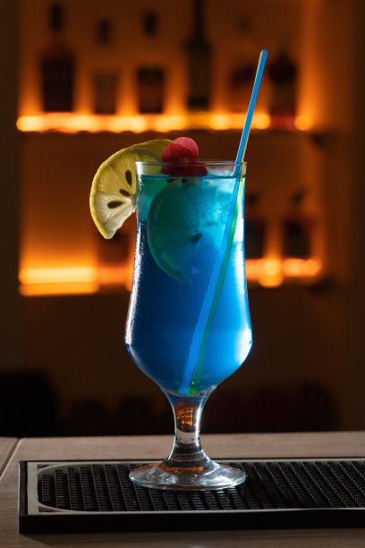 特写玻璃蓝色泻湖鸡尾酒装饰石灰在吧台背景。图片下载