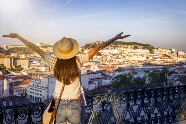 一位快乐的女游客俯瞰着里斯本五彩缤纷的老城区阿尔法玛图片下载