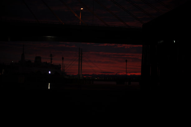 红色、粉色、橙色和紫色的日出在黎明的海边，天空中有云，海岸上有山图片下载