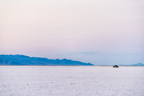 西温多弗，美国汽车行驶在犹他州盐湖城附近的白色邦纳维尔盐滩上，内华达的边界上有紫色柔和的夕阳色图片下载