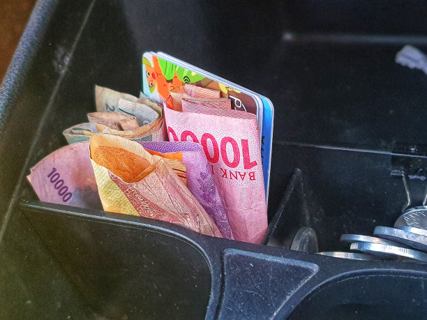 一些印尼盾硬币和10万印尼盾纸币和其他一些钱放在汽车仪表盘上的一个盒子里图片下载