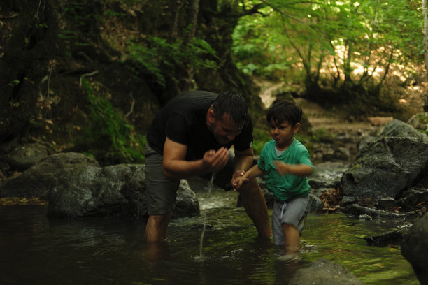 父亲和儿子在热带森林里探索河流。图片下载