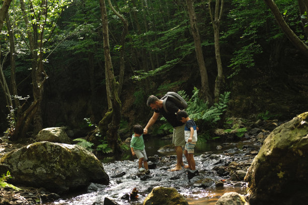 父亲和儿子在热带森林里探索河流。图片下载