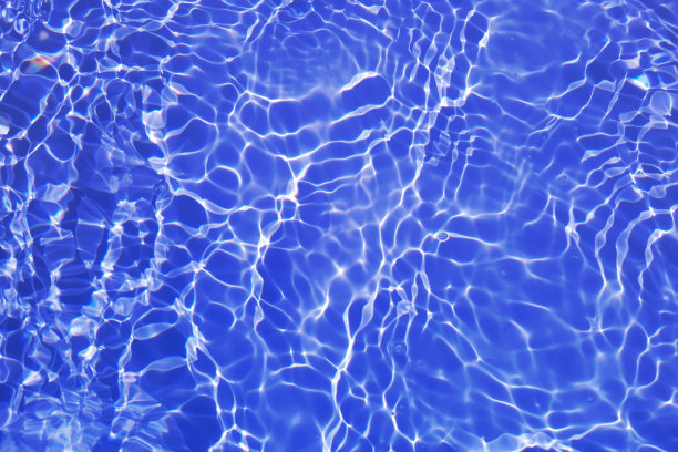 离焦模糊透明蓝色清澈平静的水面纹理与飞溅和气泡。新潮抽象的自然背景。阳光下的水波与复制空间。蓝色水彩闪闪发光图片下载