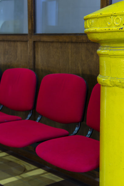邮局，等候处。红色/玫瑰色的椅子，以及黄色邮筒的一部分。图片下载