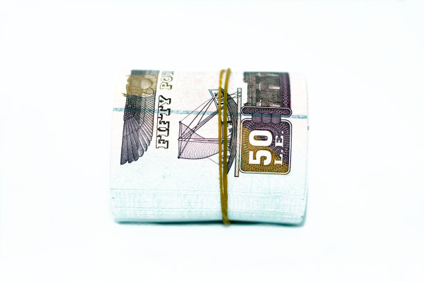 埃及钞票卷磅孤立在白色背景上，50勒50埃及镑现金纸币用橡皮筋卷起来，上面有Abu Hurayba清真寺，Edfu神庙和带翅膀的圣甲虫的形象图片下载