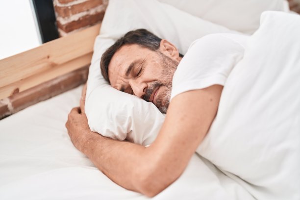 中年男子躺在床上睡觉在卧室图片下载