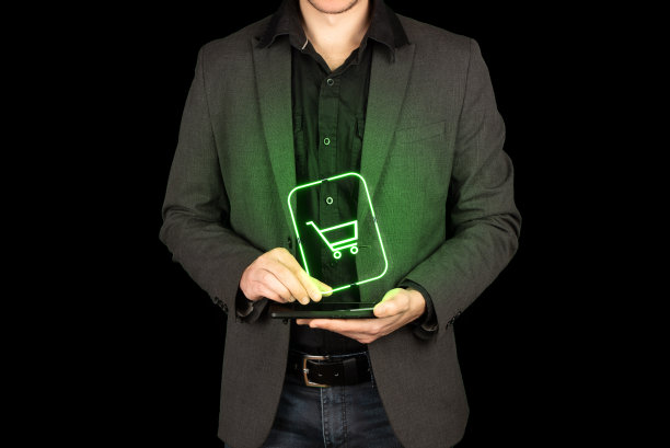年轻人在智能手机上方抓住霓虹灯购物车全息图。图片下载