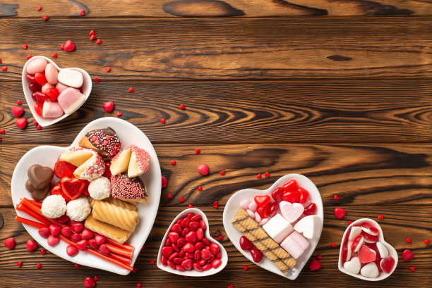 情人节庆祝概念。俯视图照片心形盘子糖果糖果和饼干在木制桌子的背景与复制空间图片下载