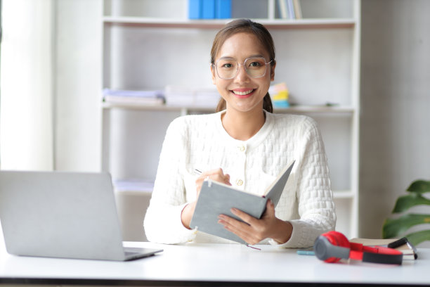 迷人的年轻女子工作与笔记本电脑在家庭办公室。图片下载