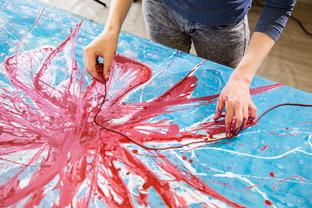 俯视图的手妇女染红油漆绘画与绳索抽象画花在蓝色，白色的画布。图片下载