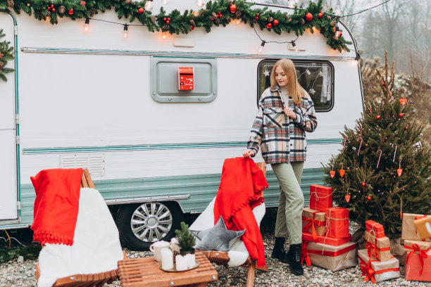 快乐的年轻女子站在现代房车附近的户外。新年和圣诞节的概念。图片下载
