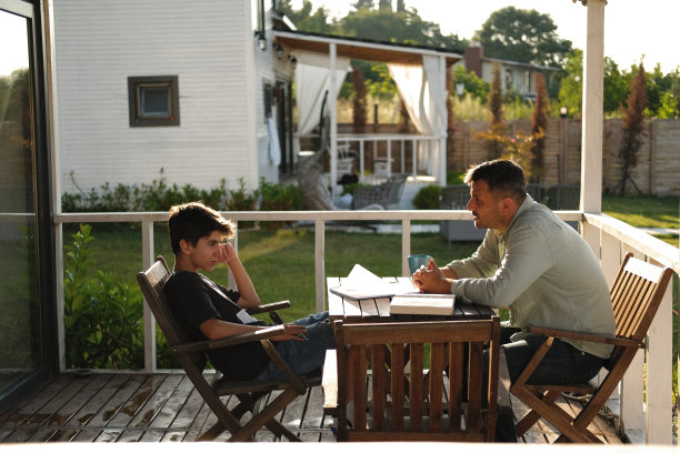 一名穿着便装的男子在田园诗般的乡村花园用笔记本电脑工作。图片下载