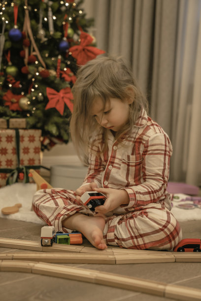 小女孩在圣诞树旁玩玩具火车图片下载