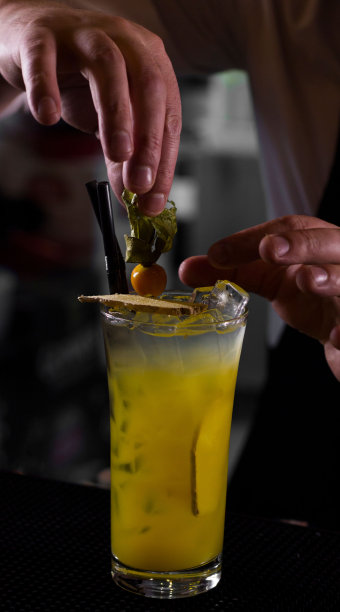 一个人在一个孤立的背景下准备新鲜菠萝鸡尾酒的垂直镜头图片下载