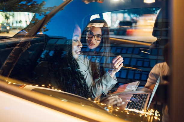 两个多种族的女商人开着车，用着笔记本电脑图片下载