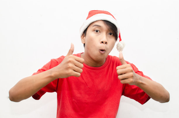 富有表现力的快乐亚洲年轻男子穿着圣诞老人主题的衣服，脸上带着震惊、惊讶和惊讶的表情。图片下载