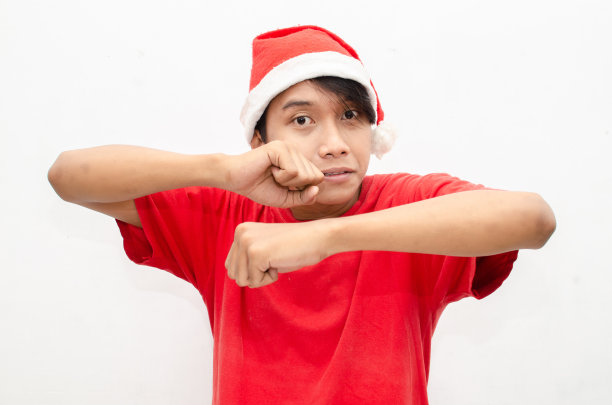 富有表现力的快乐亚洲年轻男子穿着圣诞老人主题的衣服，脸上带着震惊、惊讶和惊讶的表情。图片下载