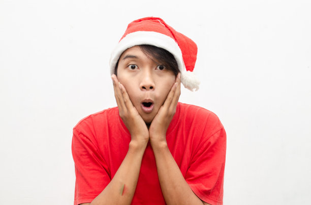 富有表现力的快乐亚洲年轻男子穿着圣诞老人主题的衣服，脸上带着震惊、惊讶和惊讶的表情。图片下载