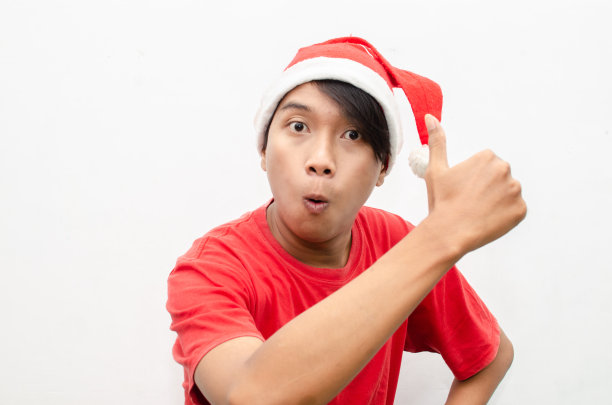 富有表现力的快乐亚洲年轻男子穿着圣诞老人主题的衣服，脸上带着震惊、惊讶和惊讶的表情。图片下载