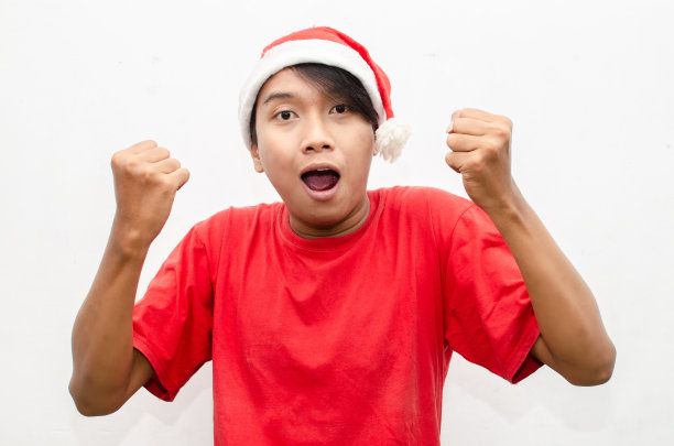 富有表现力的快乐亚洲年轻男子穿着圣诞老人主题的衣服，脸上带着震惊、惊讶和惊讶的表情。图片下载