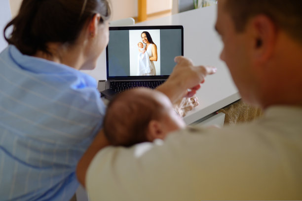 一家人在笔记本电脑上看新生儿和母亲的照片图片下载
