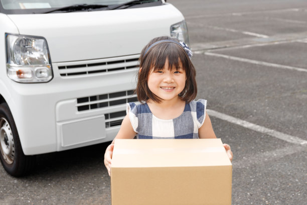 微笑的孩子从快递员那里接受包裹。接受支持和礼物的形象。图片下载