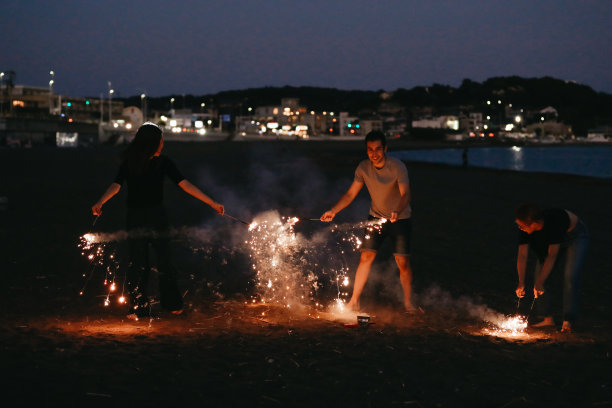 三人晚上在海滩上欣赏烟花图片下载