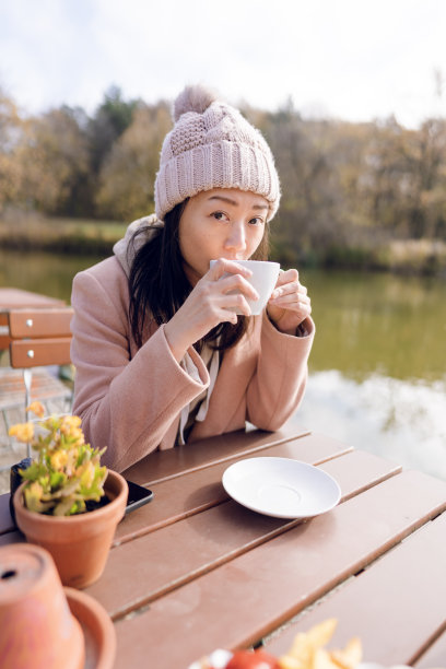 一个女人在湖边的户外咖啡馆。图片下载