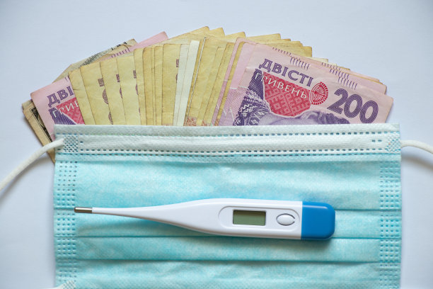 白色背景上的乌克兰格里夫纳、电子温度计和医用口罩：金融与医疗，金钱与健康图片下载