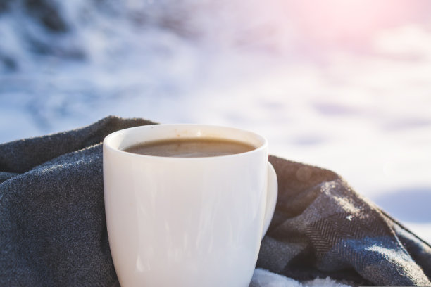 雪地里的白色杯子里装着热咖啡图片下载