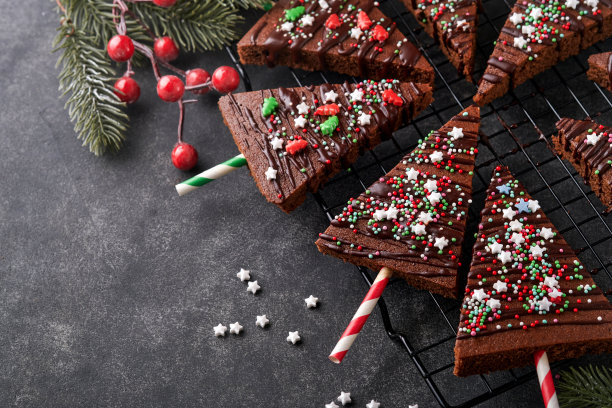 巧克力布朗尼圣诞树，石头桌子上有巧克力糖霜和节日点缀。圣诞食物创意甜蜜自制圣诞节日糕点概念。节日烹饪概念。前视图。图片下载