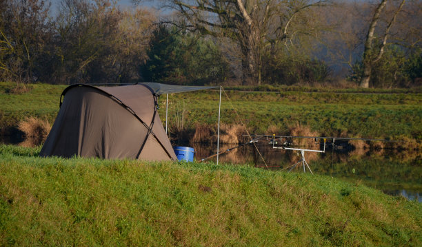 在河边钓鱼。寒冷的冬天早晨有很多阳光。有顶篷的帐篷可以御寒，睡得好。伞还可以保护垂钓者不受雨露的伤害。图片下载