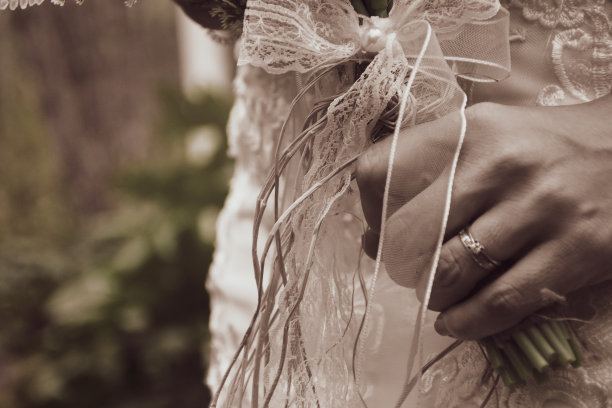 新娘手腕上戴着现代金手镯、结婚戒指和纸牌戒指，手持优雅的现代秋季婚礼花束图片下载