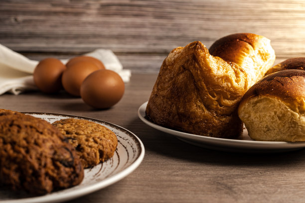 水平照片的鸡蛋，糕点，奶油蛋卷，饼干在木桌和木制背景侧照明图片下载