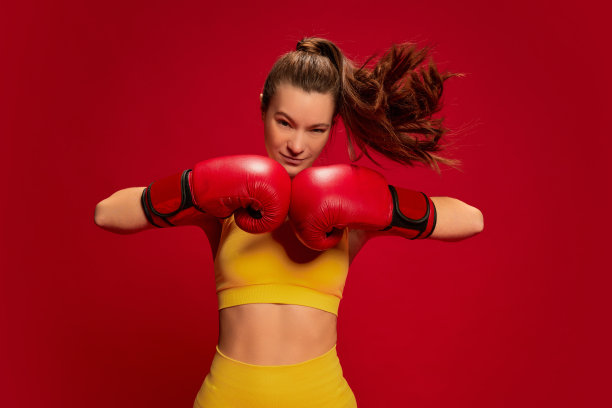 画像年轻女子在黄色运动服，拳击，训练摆姿势孤立在红色背景。力量和权力图片下载