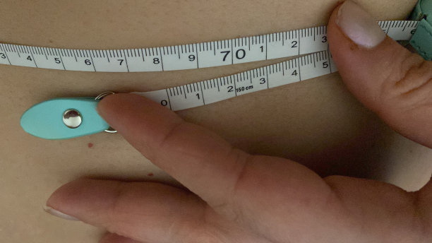 特写苗条的女人测量她的腰尺寸与卷尺图片下载