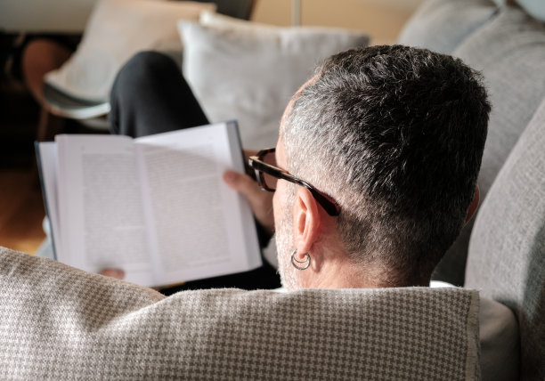 男人在沙发上看书。图片下载