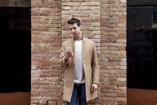 帅哥穿着外套站在户外，拿着手机图片下载