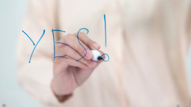 商业女性在办公室的玻璃板上写下“是”作为激励概念。图片下载