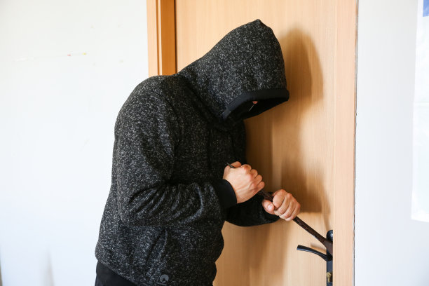 门边拿着撬棍的罪犯。强盗破门而入。图片下载