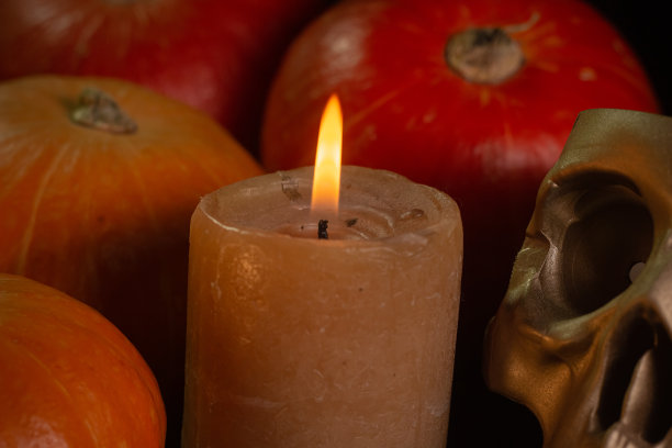 橙黄色的南瓜配上蜡烛和黑色背景上的骷髅头万圣节的概念和秋天收获的南瓜从上面的特写复制空间图片下载