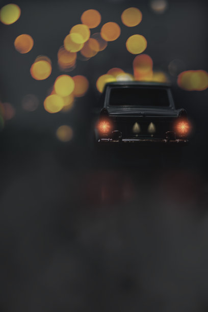 老式的黑色汽车行驶在黑暗多雾的道路上，路灯模糊不清图片下载