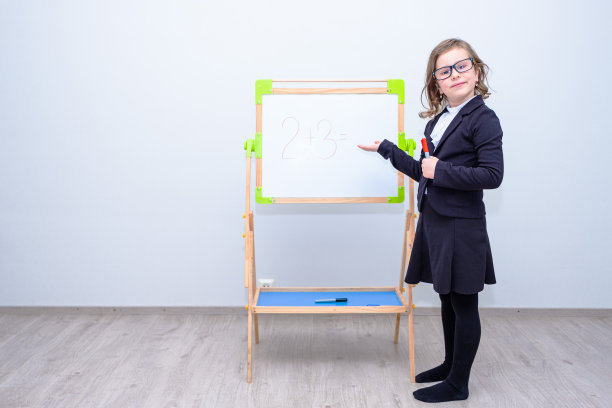 一幅肖像，一个白人女学生，站在一块白板前，用手指着它。图片下载