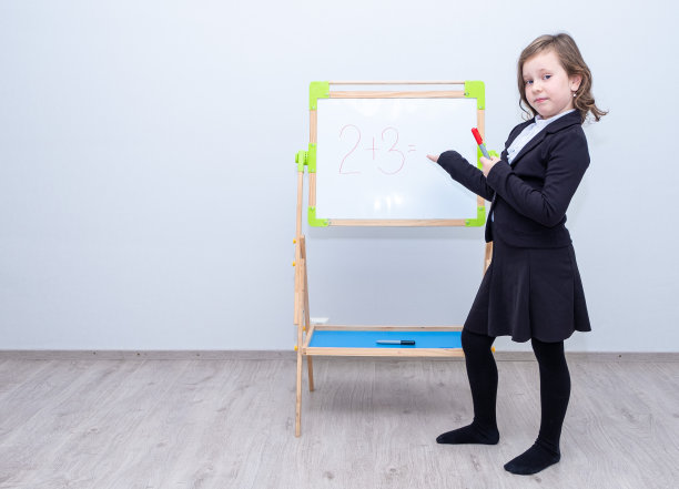 一幅肖像，一个白人女学生，站在一块白板前，用手指着它。图片下载