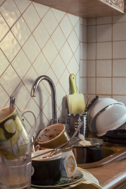 贴着瓷砖的厨房里，满是脏罐子的水槽特写。图片下载