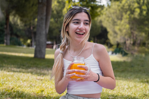户外照片，年轻和现代的妇女在大自然中喝橙汁图片下载