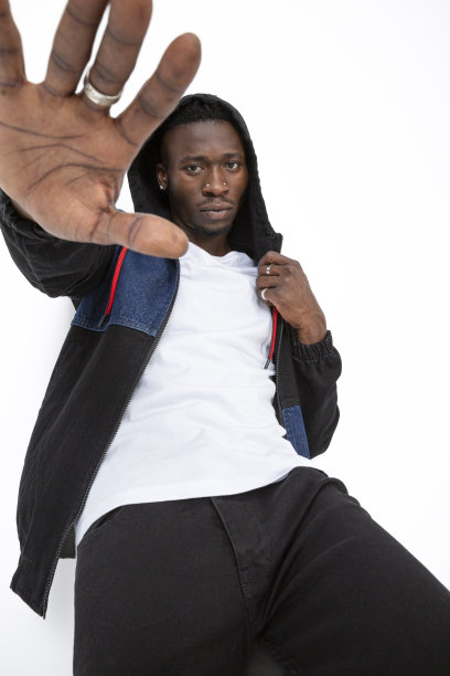 站在白人背景上的非裔美国人。穿着卫衣运动衫，白色t恤和黑色牛仔裤的酷黑人魅力男子。图片下载